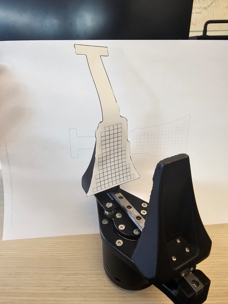 The paper cutout of the 1:1 PDF held against the gripper jaw.