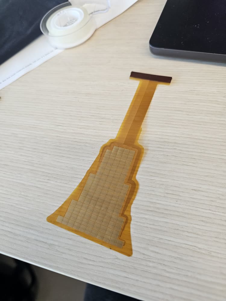 The flex PCB as delivered: yellow polyimide with a gold taxel grid and a stiffened connector end.
